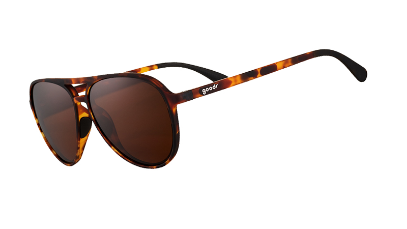 Vista en ángulo de tres cuartos de unas gafas de sol de aviador de carey marrón con cristales antirreflejantes marrones sobre fondo blanco.