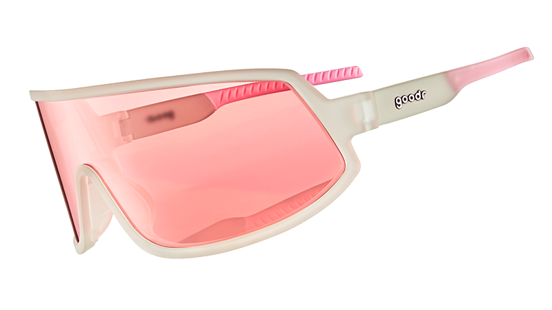 Vista di tre quarti di occhiali da sole avvolgenti con montatura trasparente e lente singola non riflettente color rosa.
