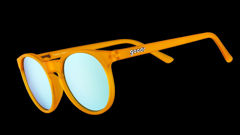 Vista en ángulo de tres cuartos de unas gafas de sol redondas de color naranja con cristales polarizados reflectantes de color azul claro.