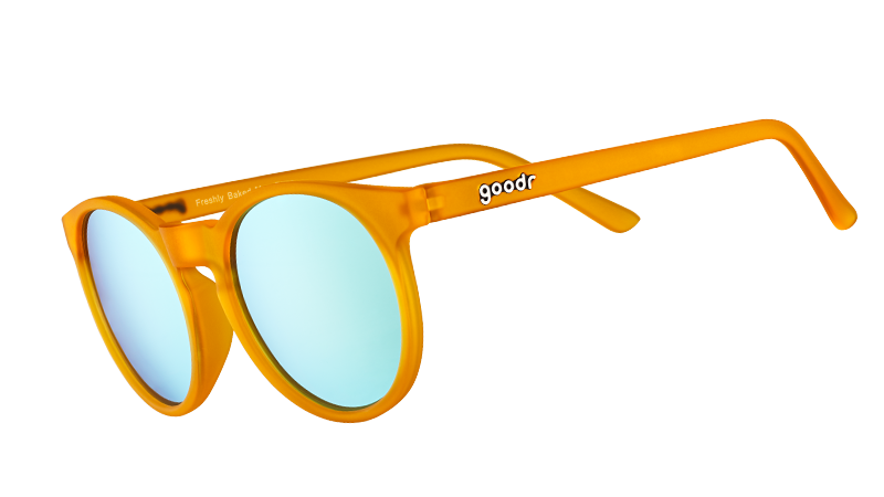 Vista di tre quarti di occhiali da sole rotondi arancioni con lenti polarizzate riflettenti blu chiaro.