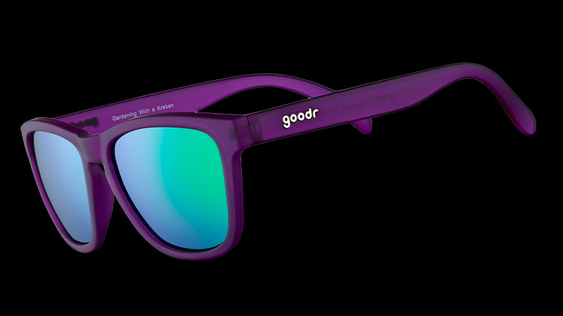 Vista di tre quarti di occhiali da sole di forma quadrata con montatura viola e lenti polarizzate verdi riflettenti.