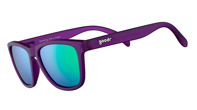 Vista di tre quarti di occhiali da sole di forma quadrata con montatura viola e lenti polarizzate verdi riflettenti.