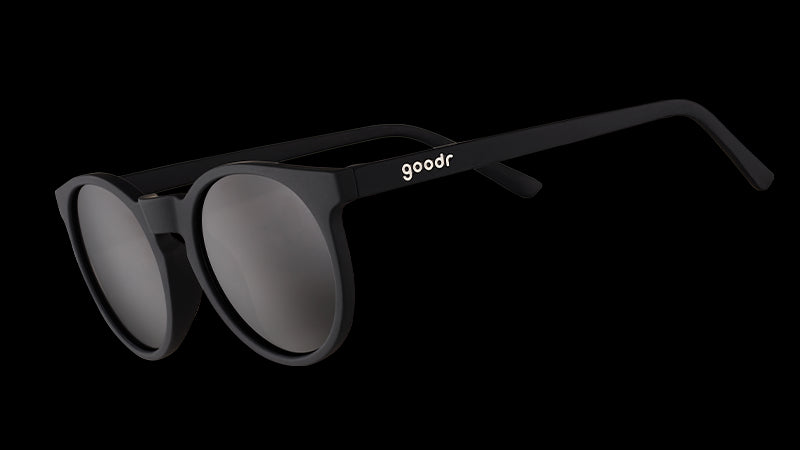 Vue de trois quarts d'angle de lunettes de soleil rondes noires d'inspiration rétro avec des verres noirs non réfléchissants.