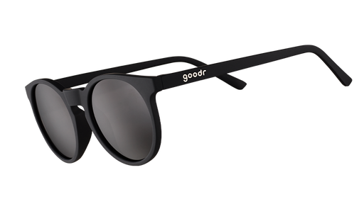 Vista en ángulo de tres cuartos de unas gafas de sol redondas negras de inspiración retro con lentes negras antirreflejantes.