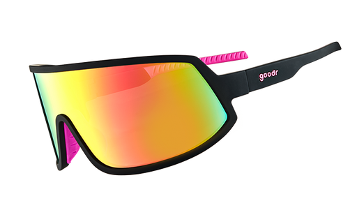 Vista di tre quarti di occhiali da sole avvolgenti con montatura nera con impugnature interne in silicone rosa caldo e una grande lente rosa. 
