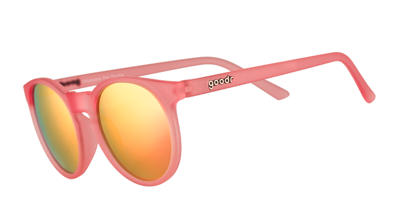 Vista de tres cuartos de unas gafas de sol redondas de color rosa con lentes polarizadas de espejo rosa.
