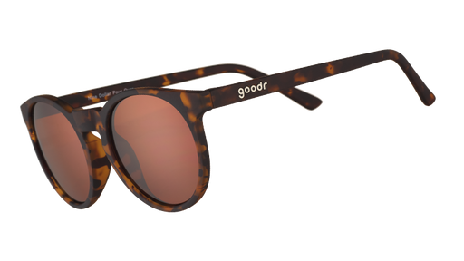 Vista en ángulo de tres cuartos de unas gafas de sol redondas de carey marrón con cristales circulares marrones antirreflejos.
