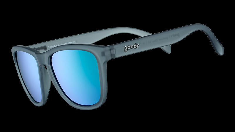 Vista di tre quarti di un occhiale da sole di forma quadrata con montatura traslucida grigia e lenti riflettenti verdi.