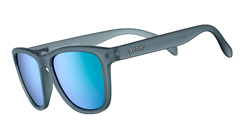 Vista di tre quarti di un occhiale da sole di forma quadrata con montatura traslucida grigia e lenti riflettenti verdi.