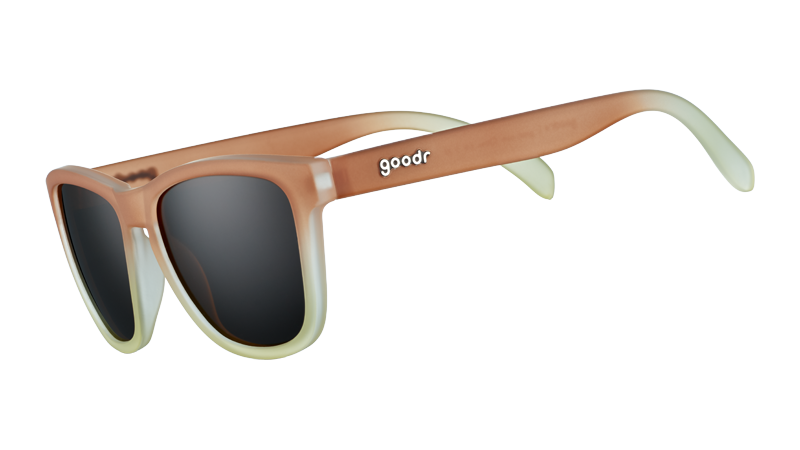 Vista di tre quarti di occhiali da sole di forma quadrata con montatura sfumata dal marrone al bianco e lenti marroni non riflettenti.
