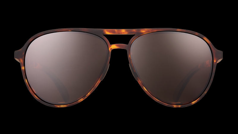 Vista frontal de unas gafas de sol de aviador de carey marrón con cristales antirreflejantes marrones sobre fondo blanco.