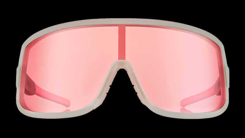 Vista frontal de unas gafas de sol envolventes con montura transparente y lente única tintada en rosa.