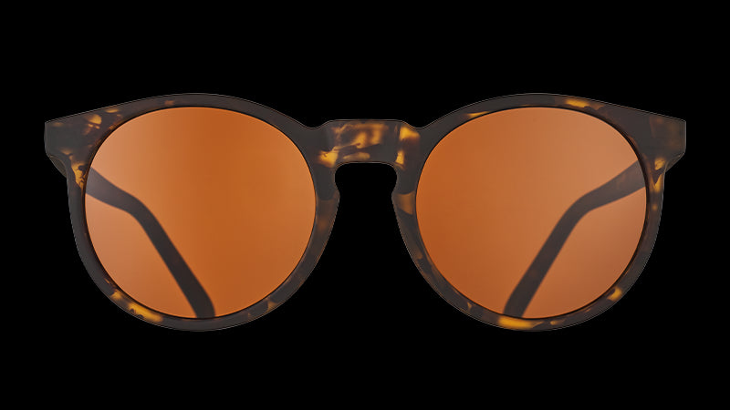 Vista frontale di occhiali da sole rotondi in tartaruga marrone con lenti marroni non riflettenti a forma di cerchio.