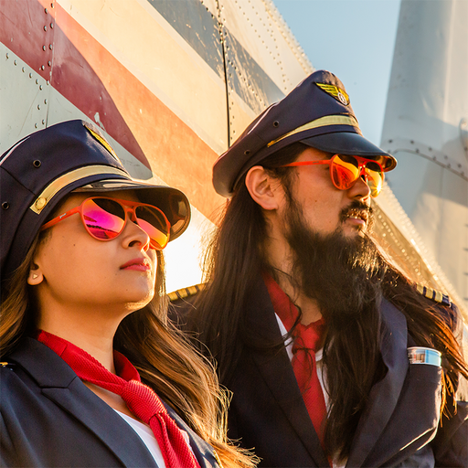 Zwei zerzauste Piloten mit roten Fliegersonnenbrillen mit roten Gläsern lehnen an einem Flugzeug und schauen in den Sonnenuntergang.